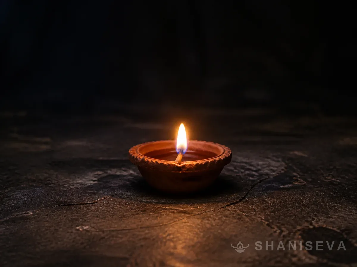 A single clay lamp burning on dark stone