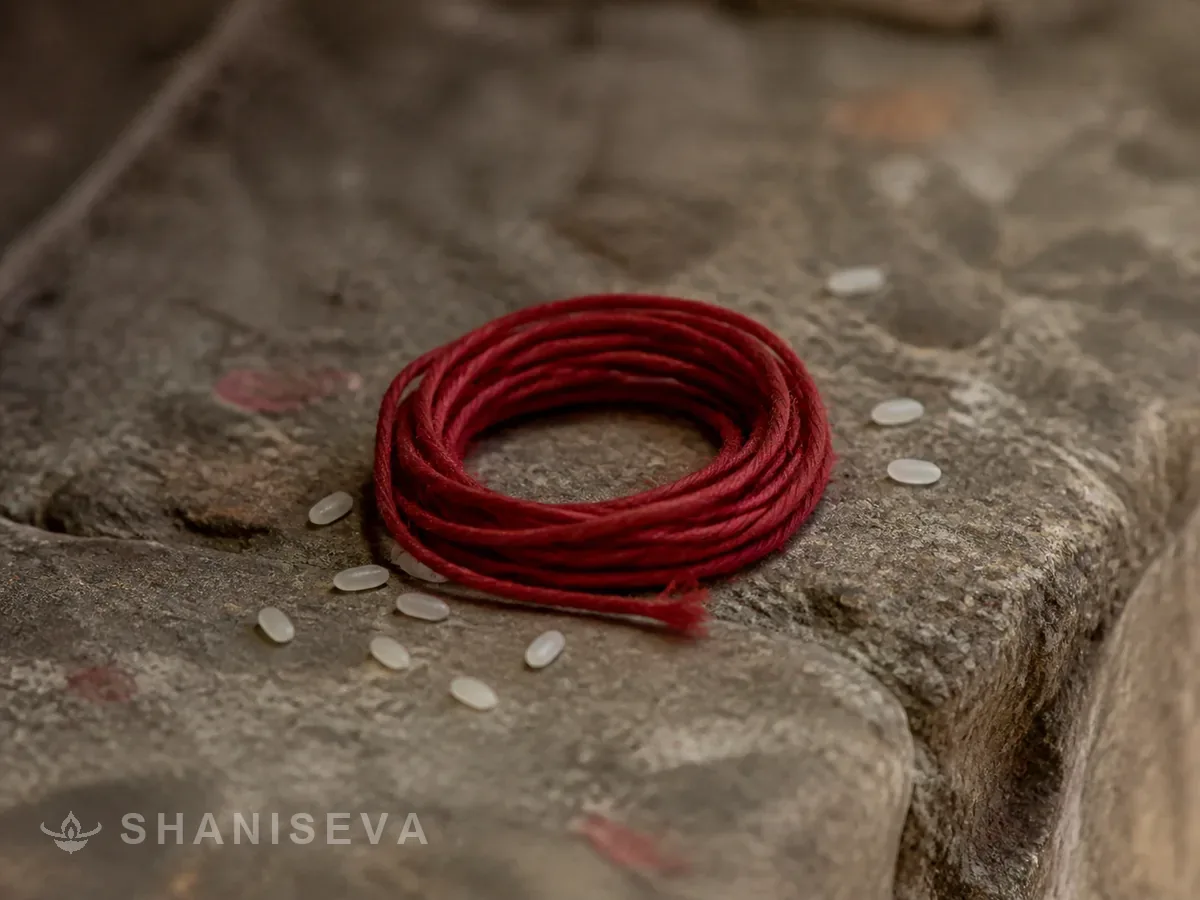 Red thread and rice grains on worn stone